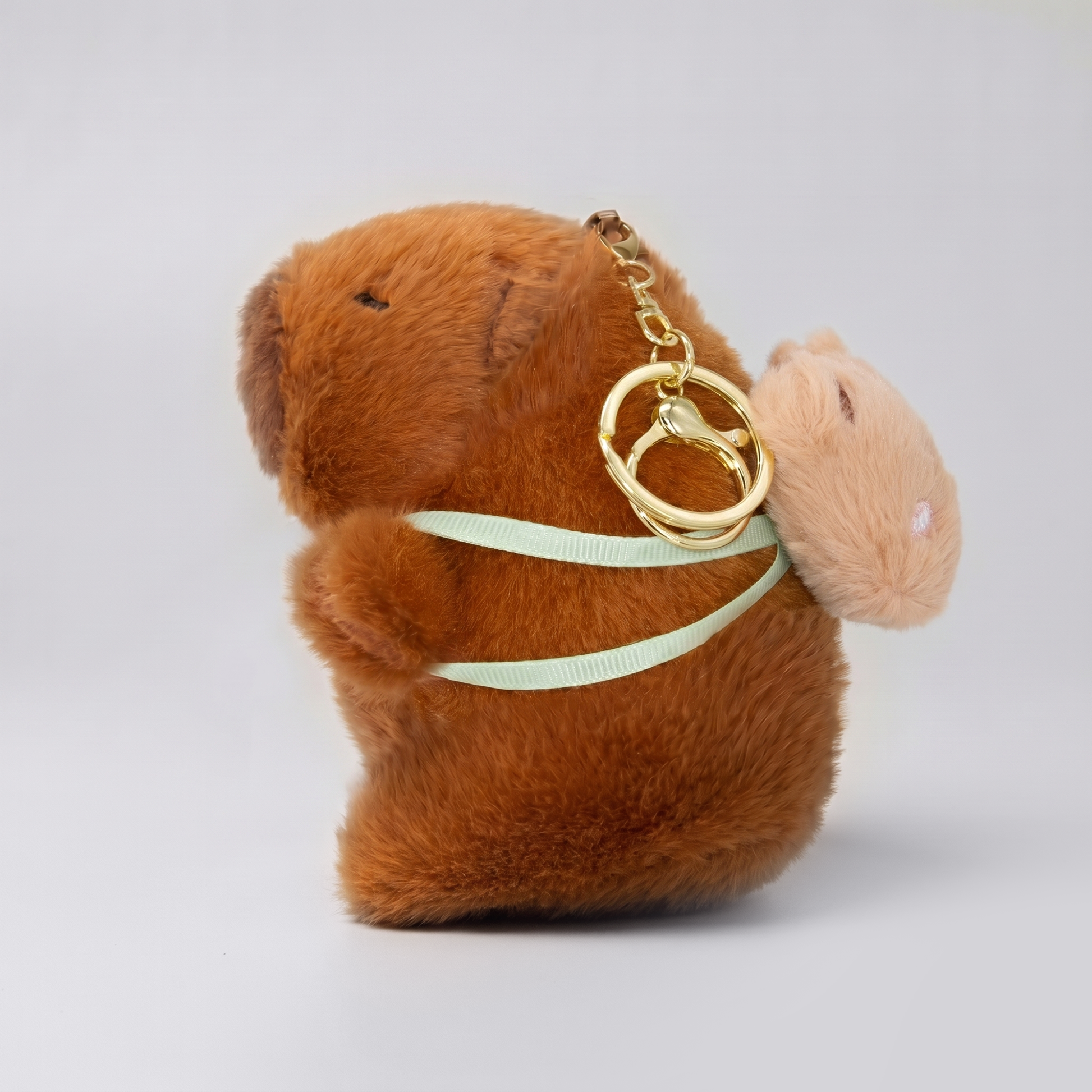 Soft capybara keychain wearing a cute bear shaped backpack with a gold keyring keychain