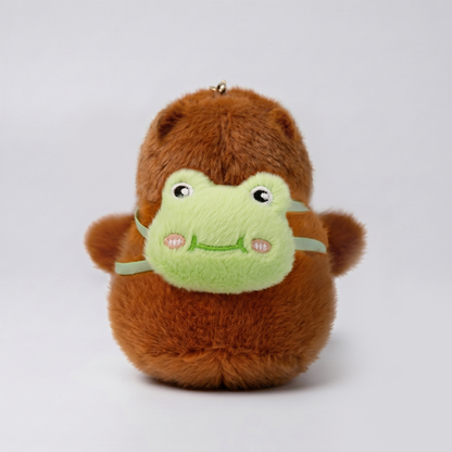 Soft capybara keychain wearing green frog backpack