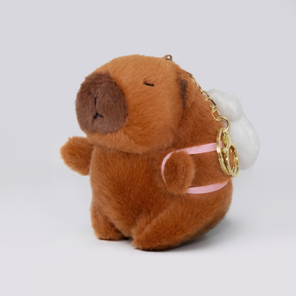 Soft capybara plush keychain wearing a rabbit plush shaped backpack with pink straps and a gold keyring keychain 