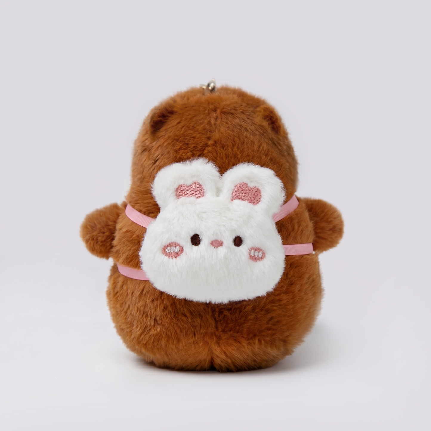 Soft capybara plush keychain wearing a rabbit plush shaped backpack with pink straps 