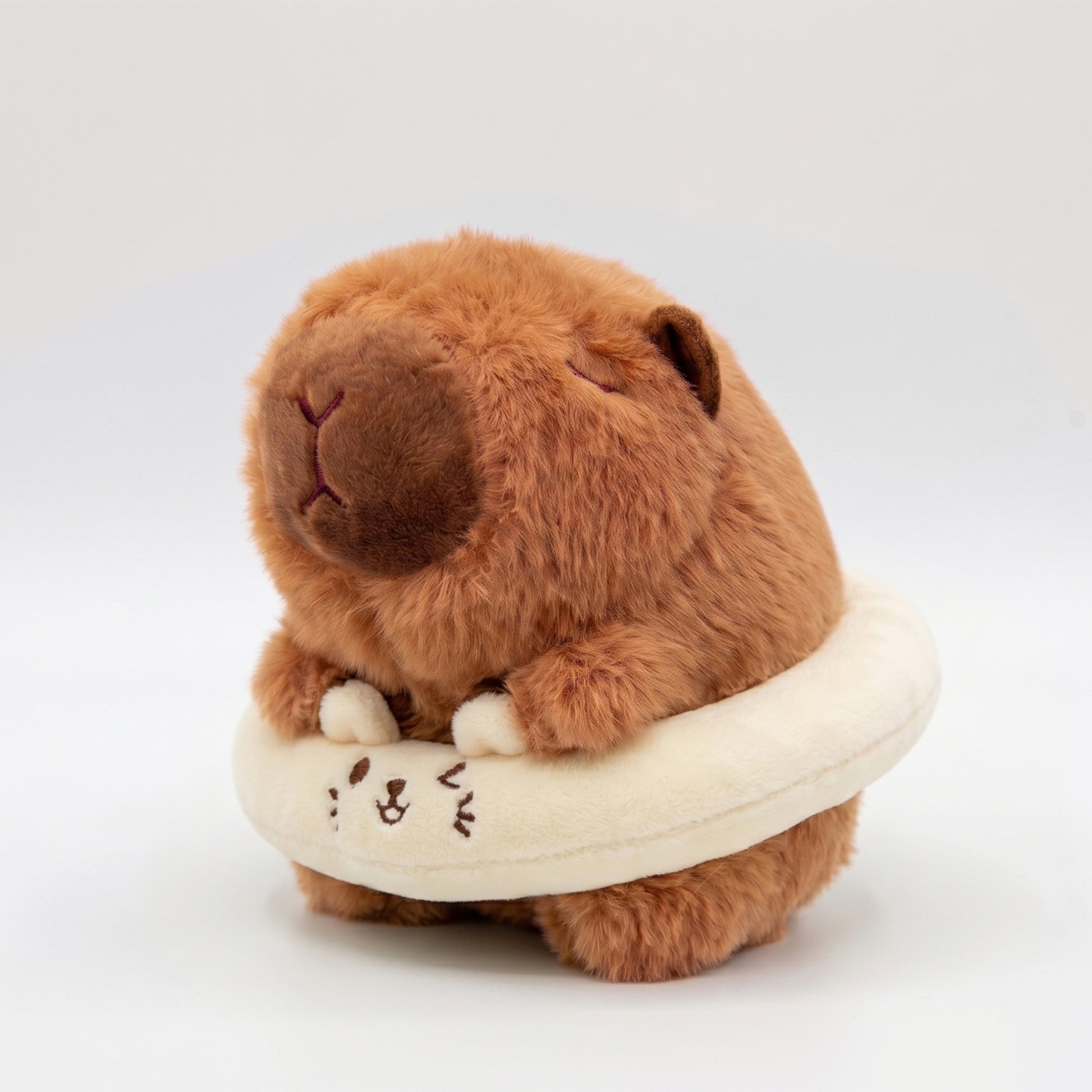 Fluffy capybara plush toy wearing a cream floatie ring
