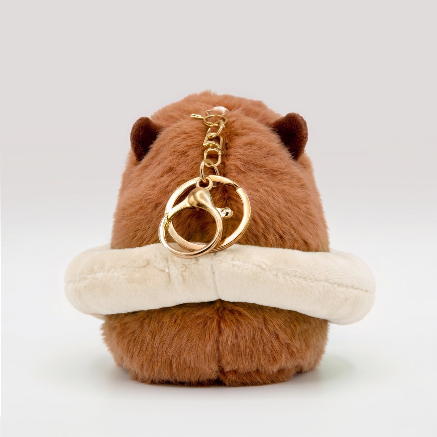 Fluffy capybara plush toy wearing a cream floatie ring featuring a gold metal key ring