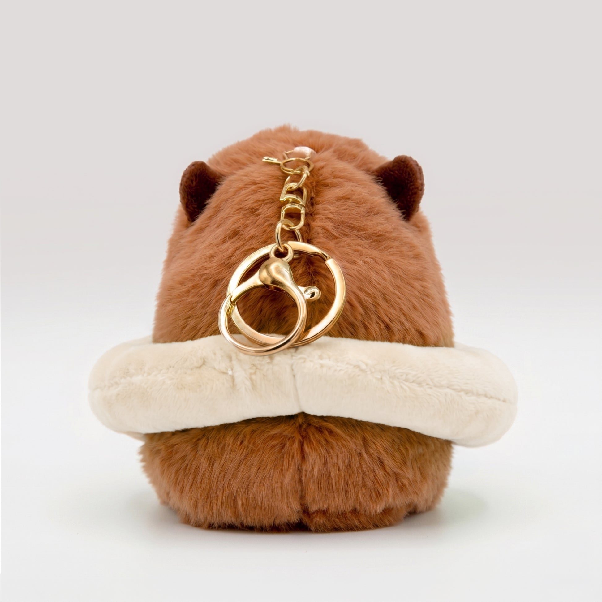 Fluffy capybara plush toy wearing a cream floatie ring featuring a gold metal key ring