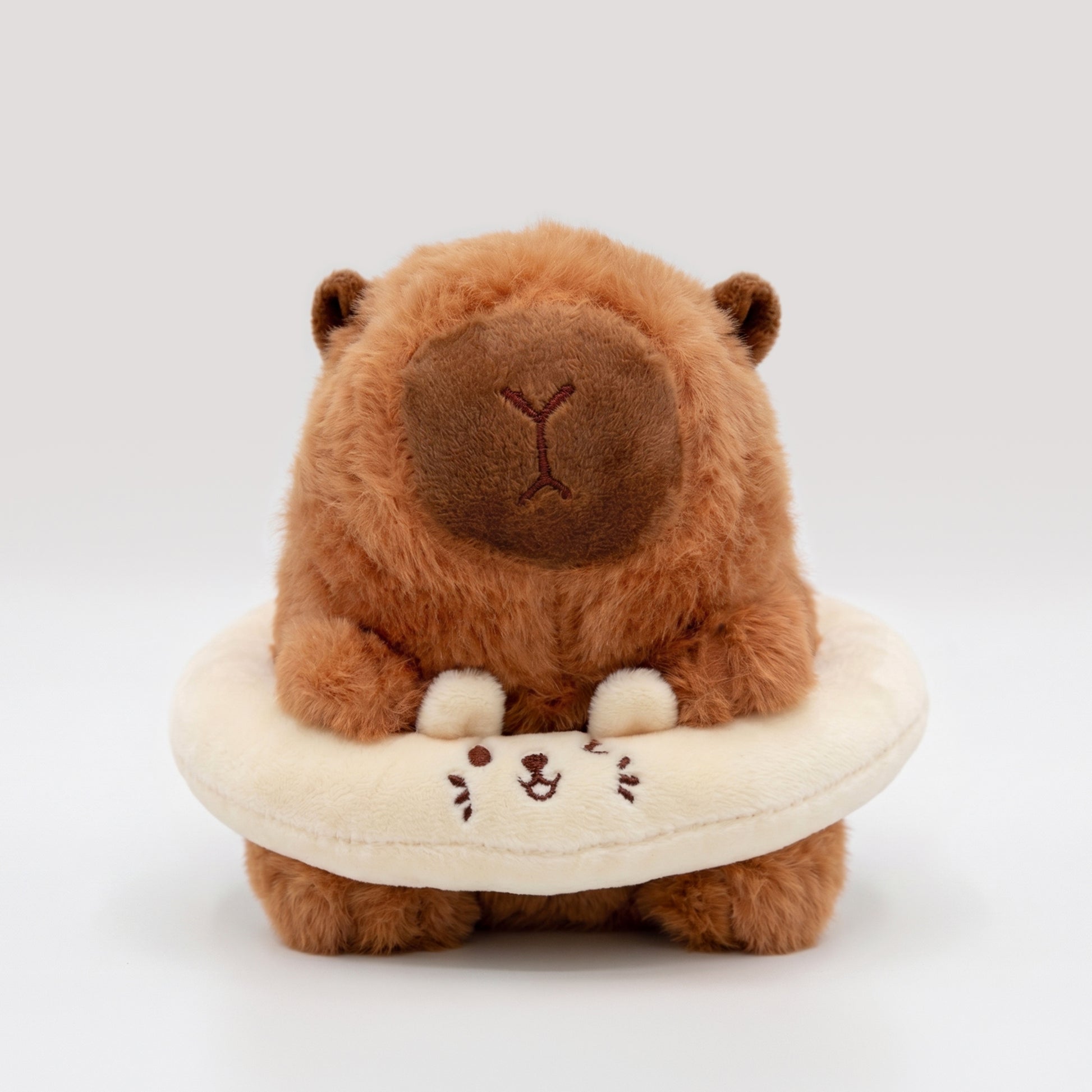 Fluffy capybara plush toy wearing a cream floatie ring featuring bunny ears and winking face