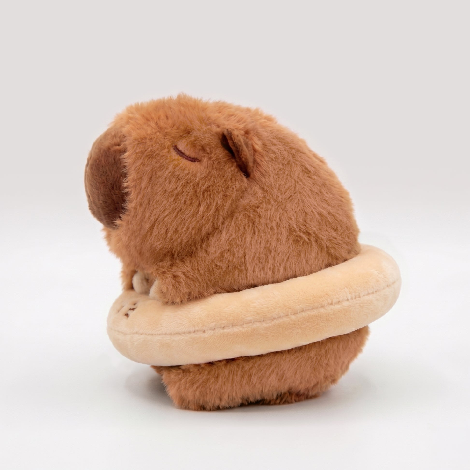 Side view of ute capybara plush wearing a cat floatie 