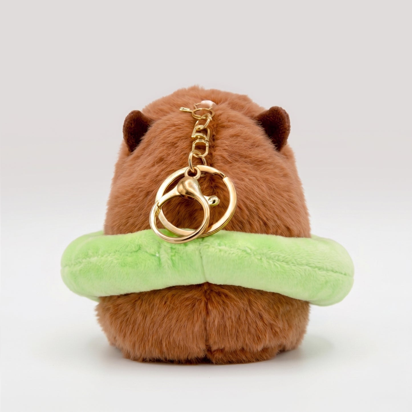 Back view of soft Capybara plush wearing a bright green floatie with a gold key ring keychain