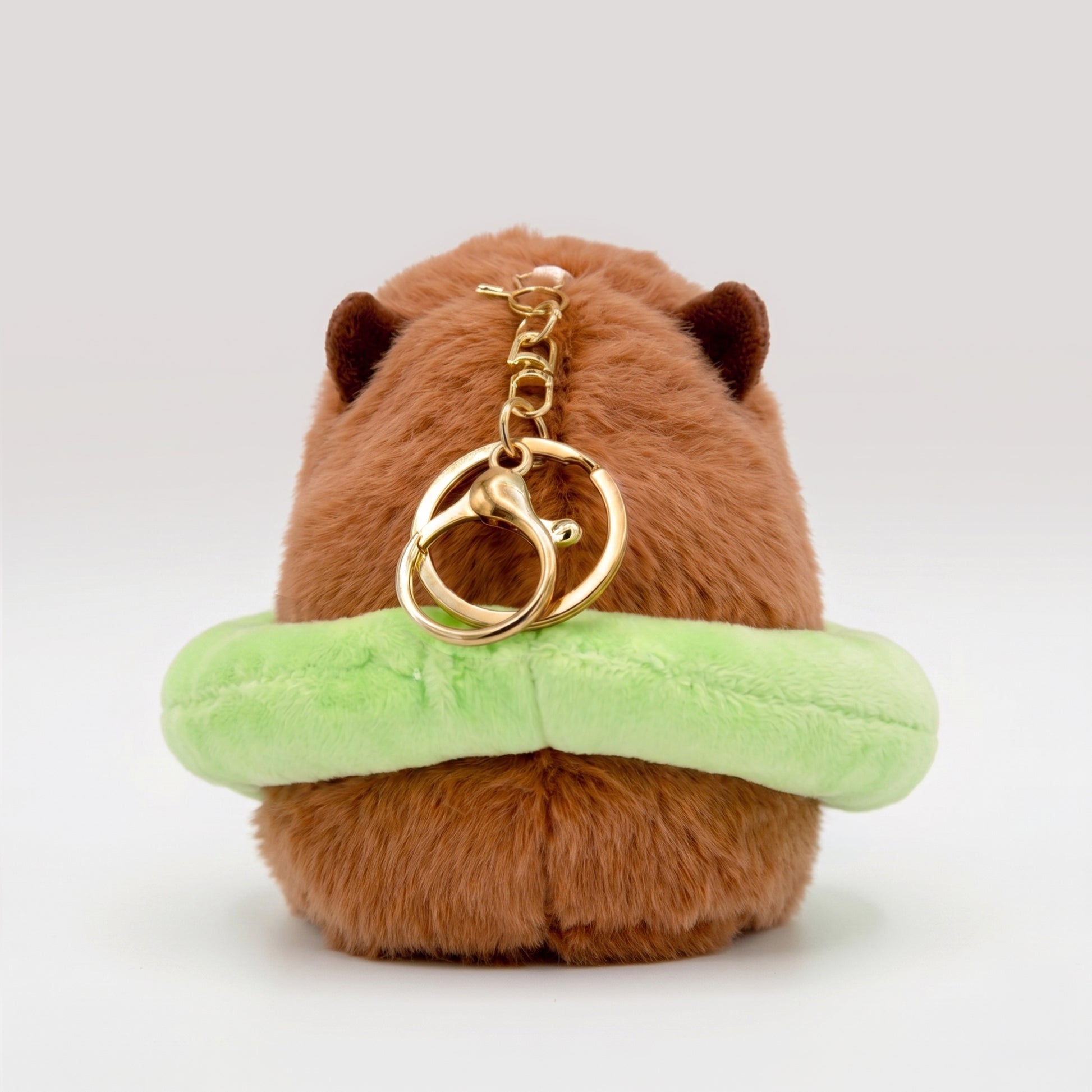 Back view of soft Capybara plush wearing a bright green floatie with a gold key ring keychain