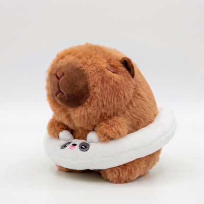 Soft capybara plush wearing a white plush floatie with a panda face on a white background