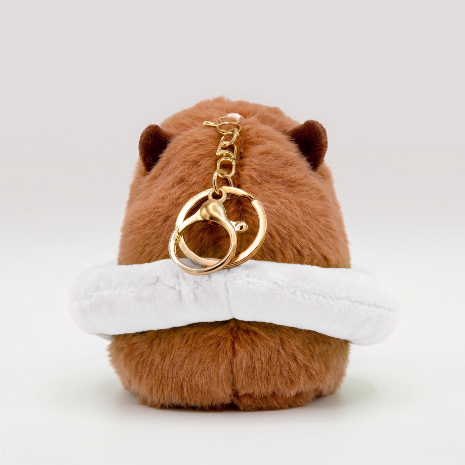 Back view of soft capybara plush wearing a white plush floatie with a gold keyring keychain on a white background
