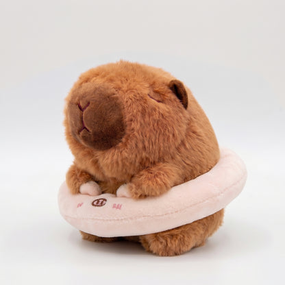 Soft capybara plush keychain wearing a pink plush floatie with a cute pig face 