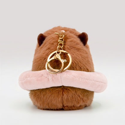Soft capybara plush keychain wearing a pink plush floatie with a cute pig face and a gold keyring keychain