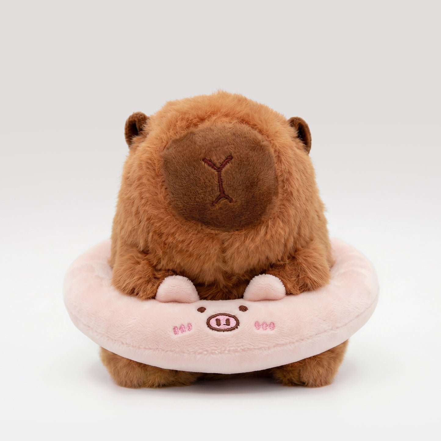 Ultra-soft Capybara plush wearing a pink plush floatie with a pig face
