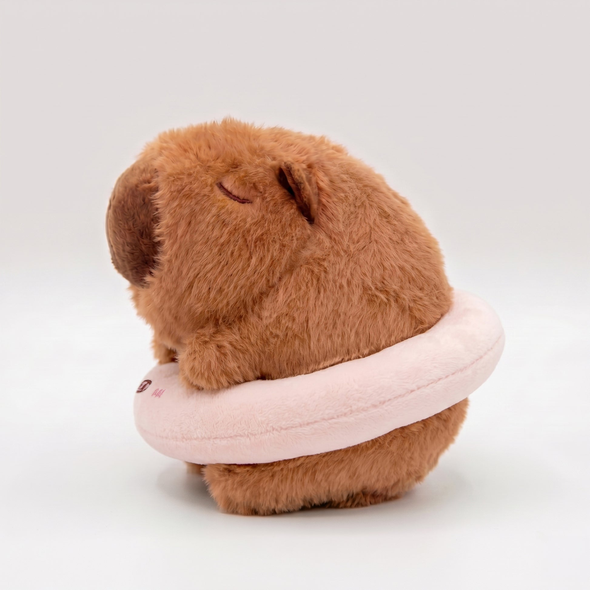 Soft capybara plush keychain wearing a pink plush floatie with a cute pig face 