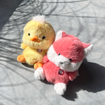 Red Fox Puff Little besides a yellow Duck Puff Little in outside setting, gray cement background