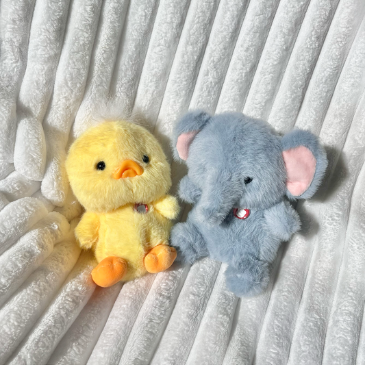 Duck Puff Little besides Elephant Puff Little on white ribbed blanket in lifestyle blanket