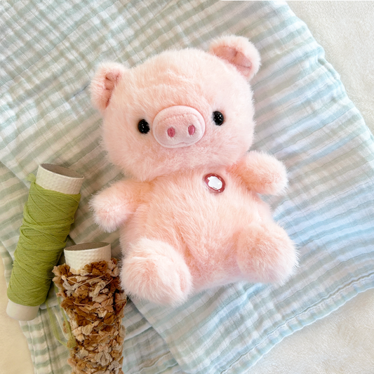 Plush pig with green and brown spools on a striped textured blanket