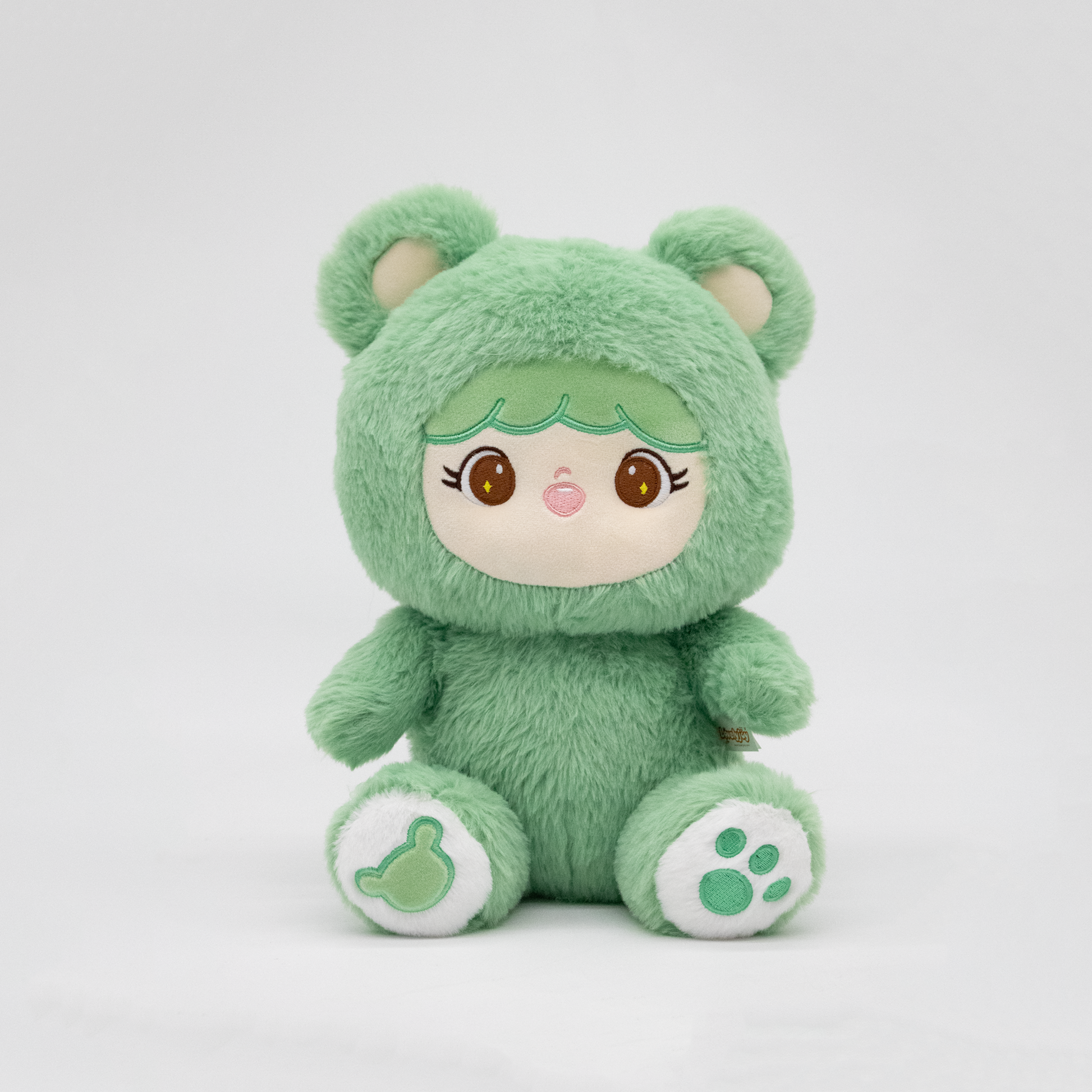 Green Sprout Shoobi plush bear with ears, white and cream details on white background