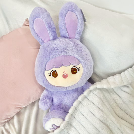 Shoobi in lifestyle setting slightly under blanket on a bed